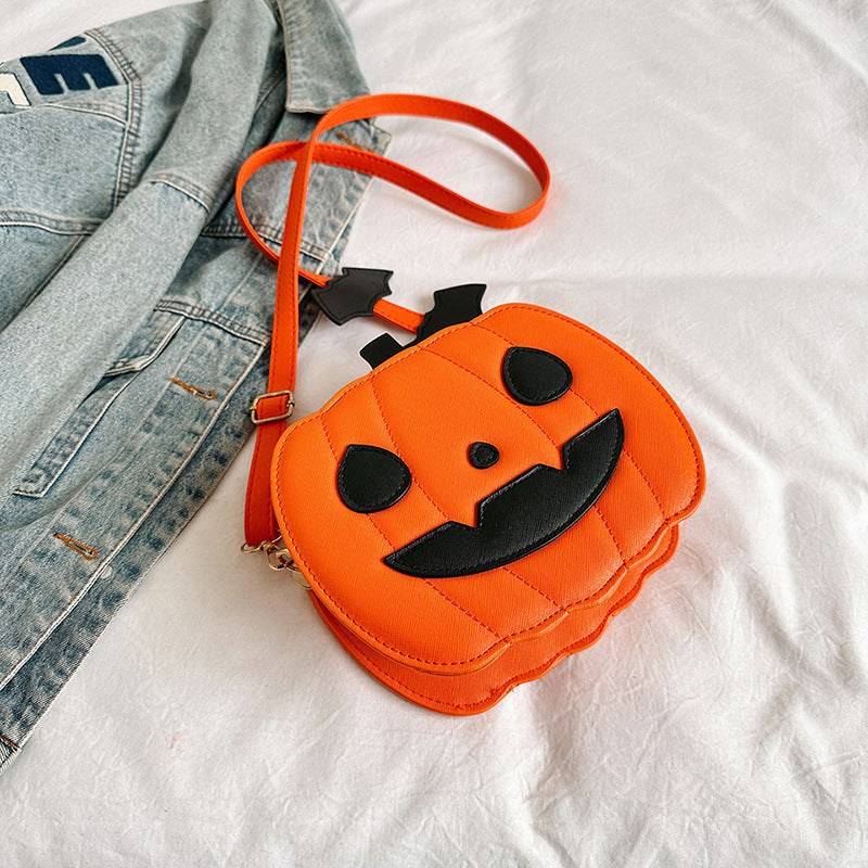 Orange Halloween crossbody bag shaped like a pumpkin with black facial features and bat-shaped strap accessory