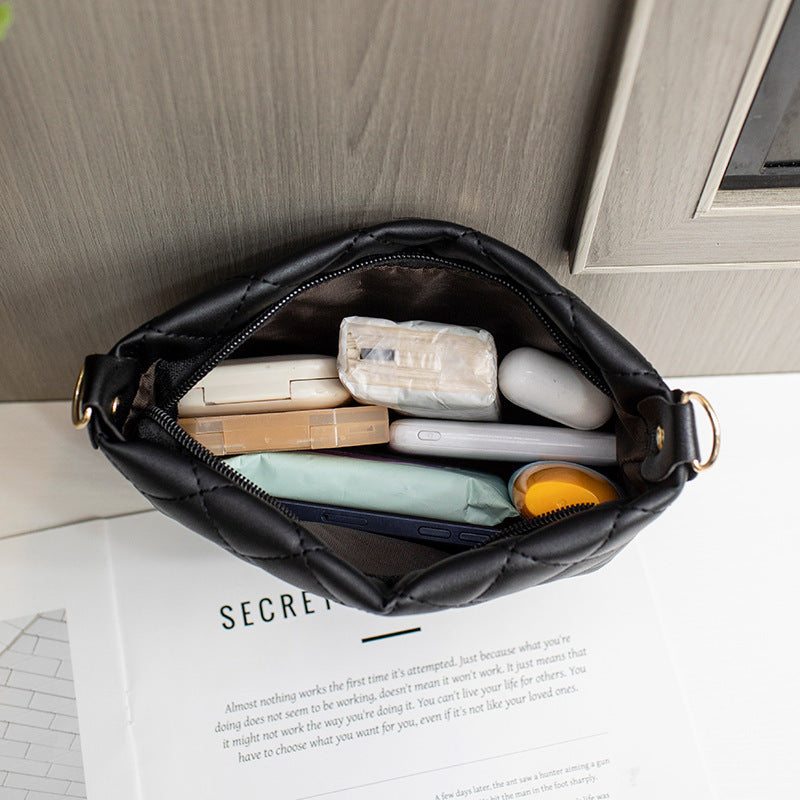 black small messenger bag with lingge embroidery and chain strap, open top showing compact essentials inside