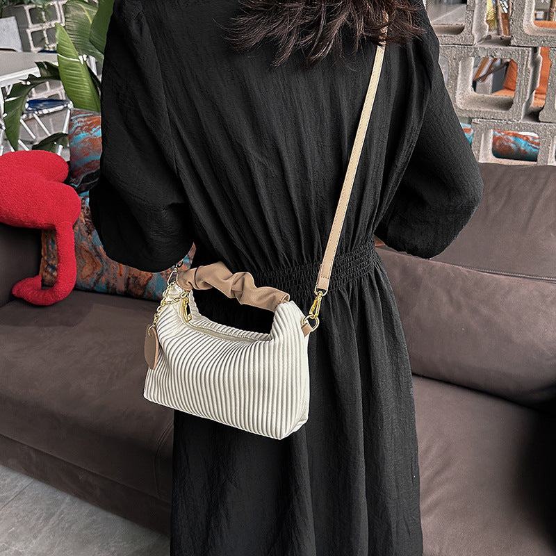 Women fashion crossbody bag in pleated white PU leather with adjustable strap on woman in black dress