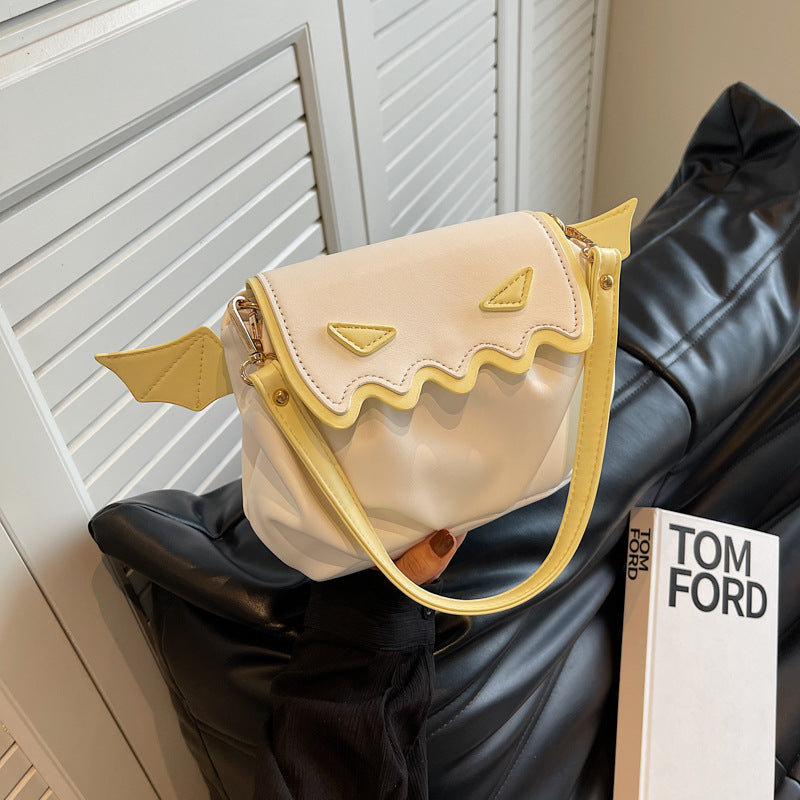 Funny crossbody bag with pumpkin face and small wings in cream and yellow colors